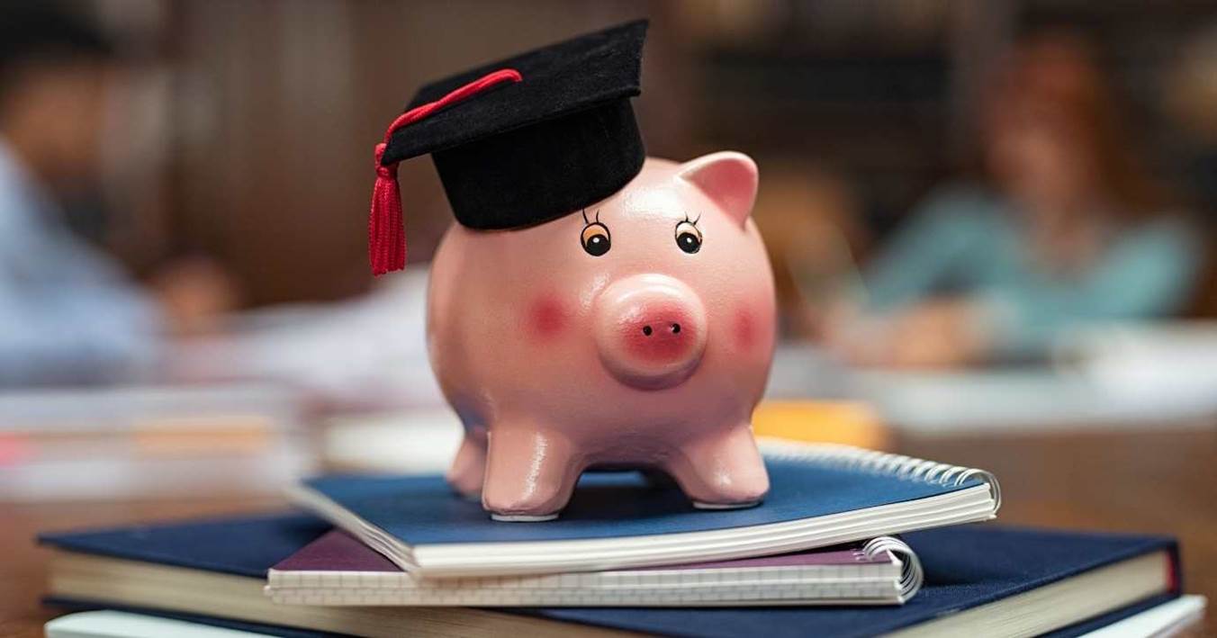 Piggy Bank With Graduation Cap On Books