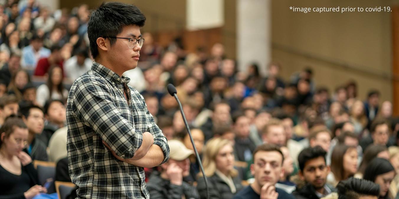 Student Standing In Front Of Microphone At Conference