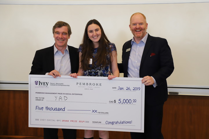 Three people holding a cheque