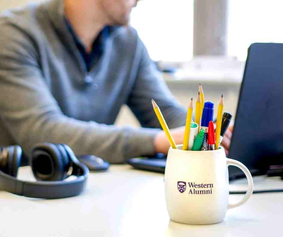 Student Working On Laptop With Western Alumni Pencil Mug In Photo