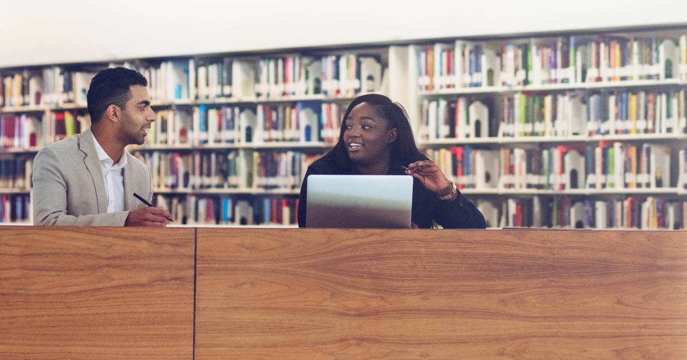 Two Students Chatting In A Library