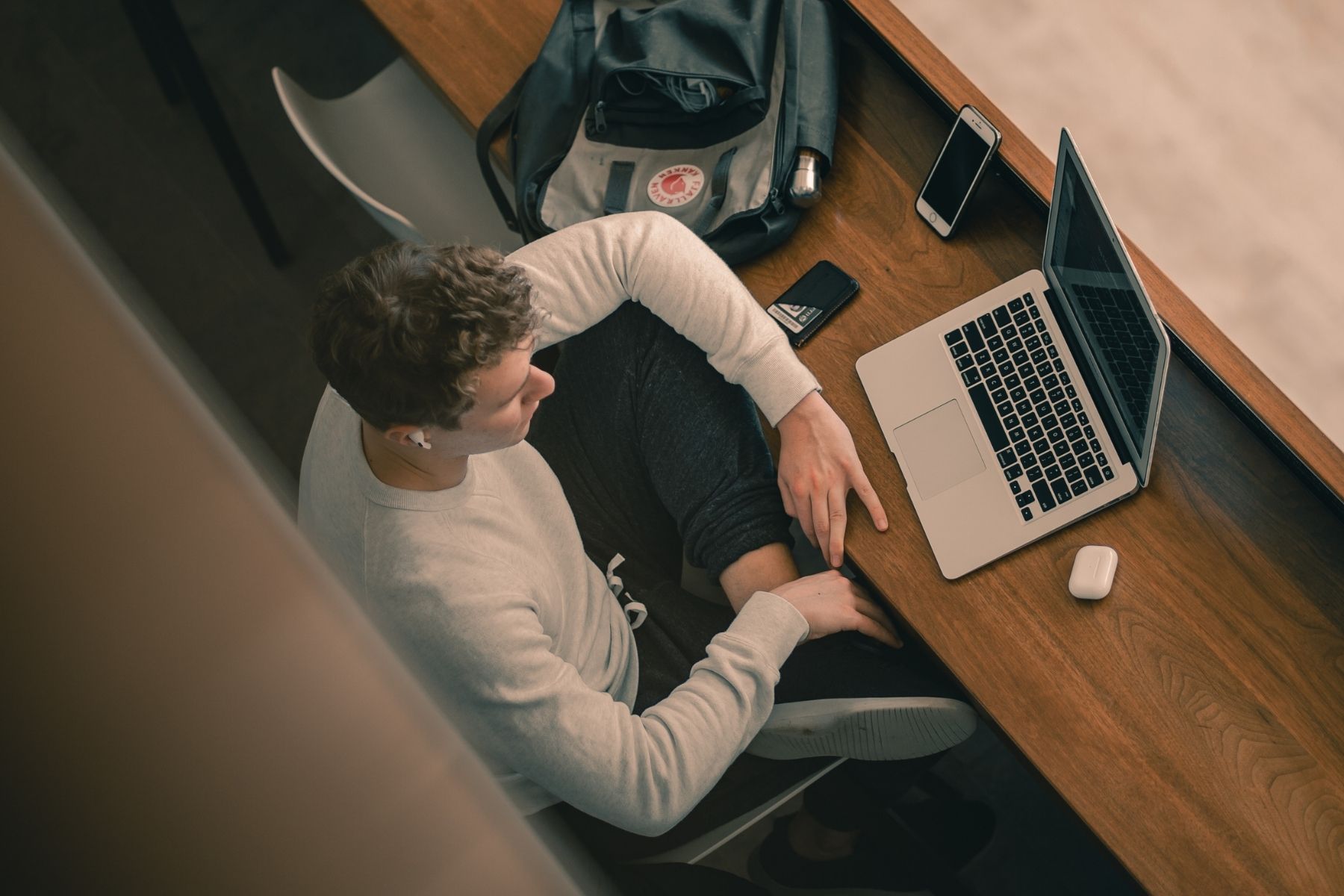 Male student sitting and working on laptop with legs crossed