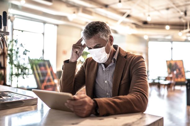 Man With A Mask Reading A Tablet