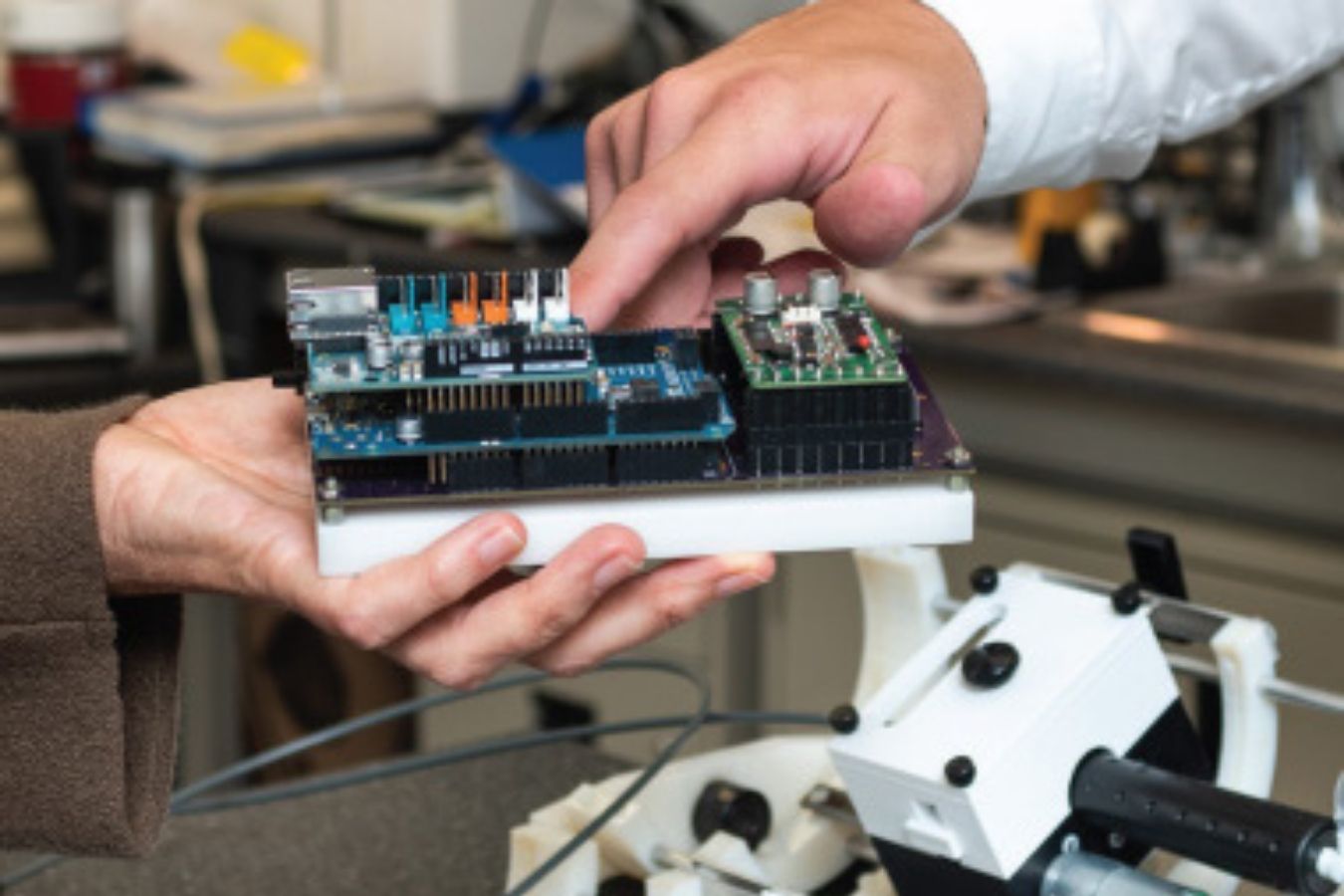 Hands touching a tech prototype device